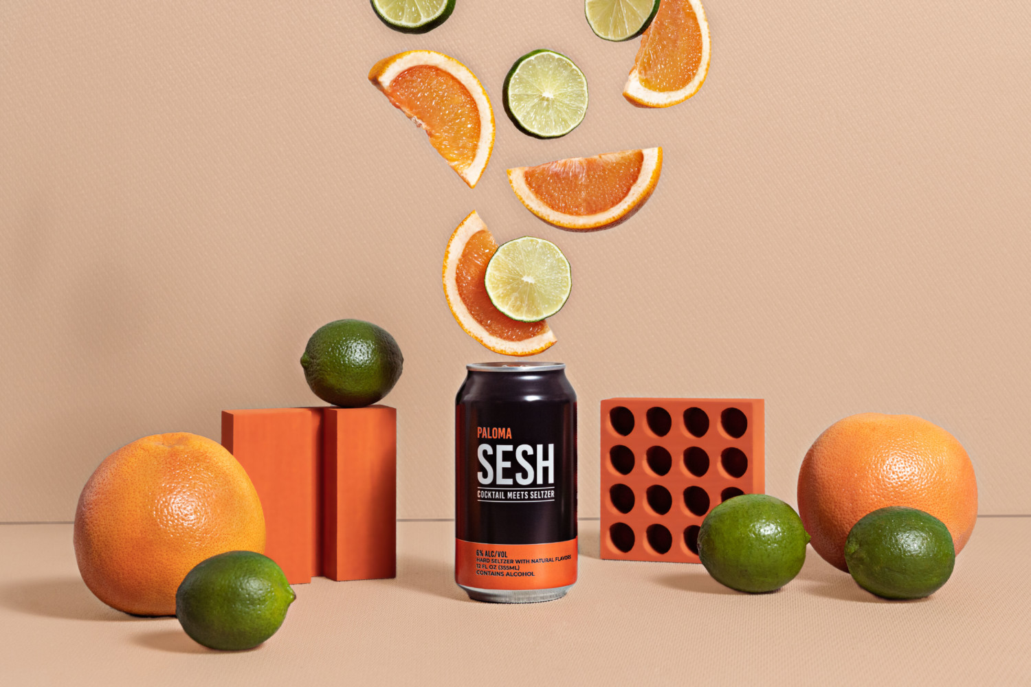 Sesh Cocktail Seltzer photographed in an orange background with lemon and lime.