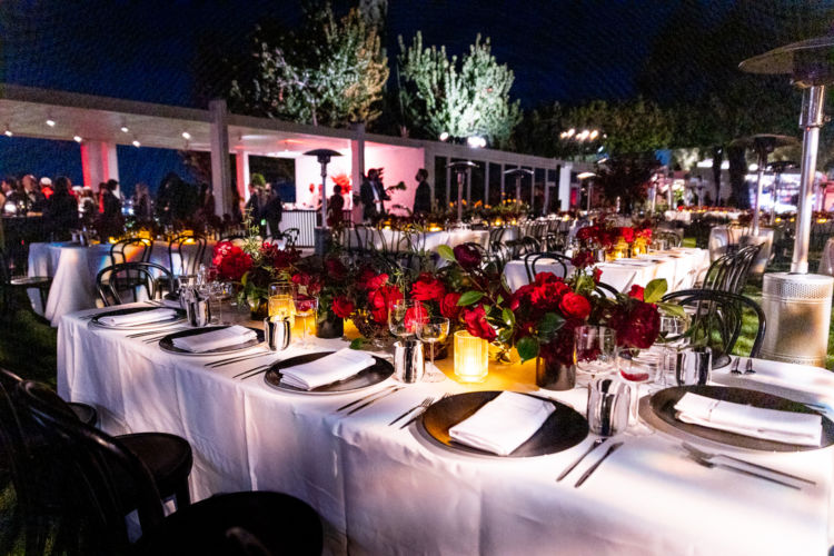 Tables with red roses centerpieces at the Savore Culinary Hermes Event.