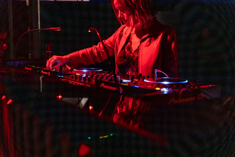 A DJ photographed under red lights at the Savore Hermes event.