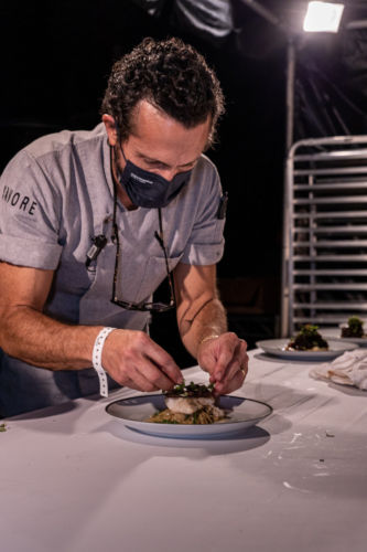 A Savore chef adding finishing touches to a dish at the Savore Hermes event.