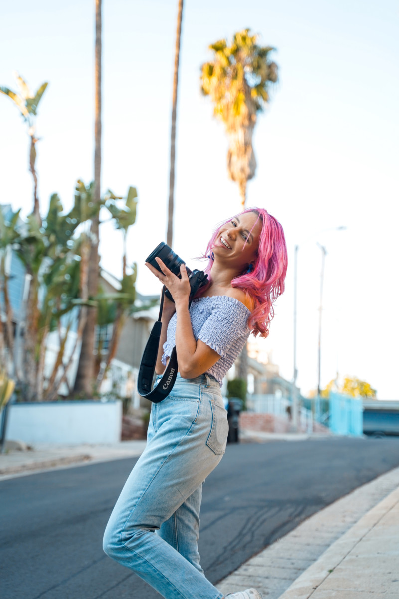 Christina Russo holding a camera and smiling for the photo.