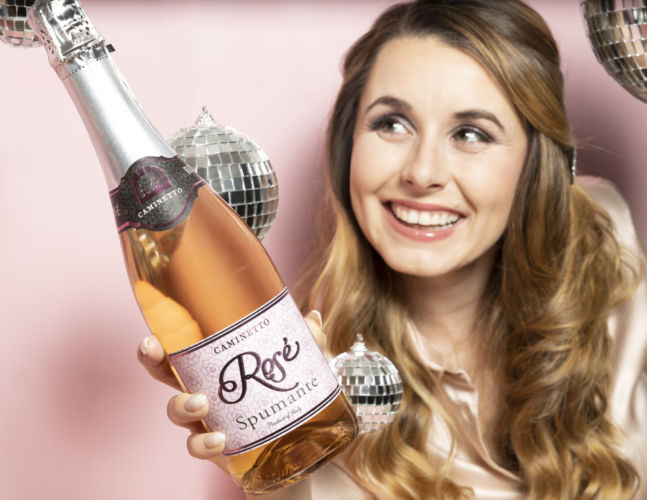 A model holding out a Caminetto wine to the camera.