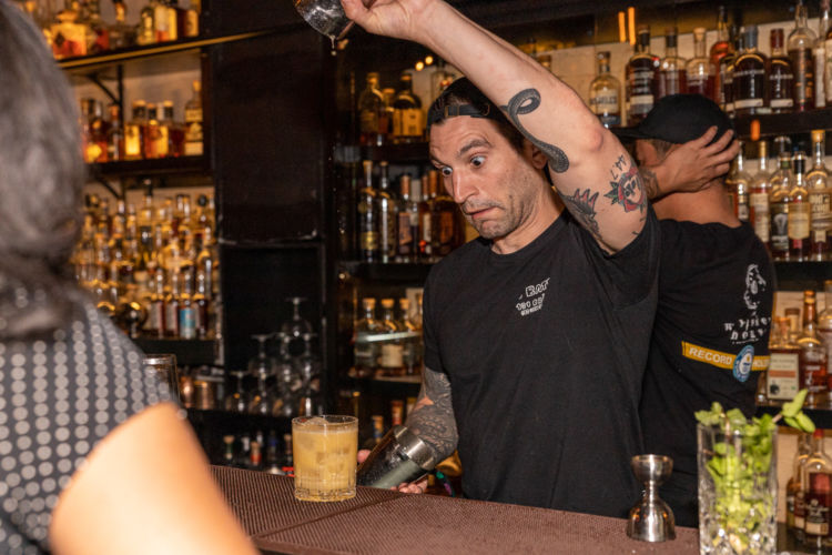 A bartender prepares a yellow drink.