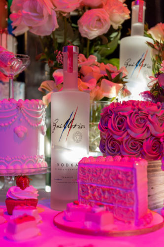 Guillotine vodka photographed with desserts and flowers.
