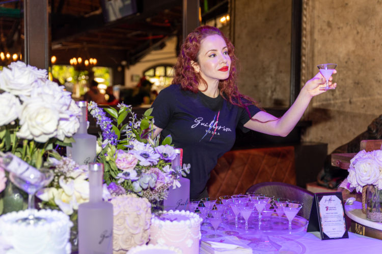A woman giving out samples of the Guillotine Vodka for the event guests at The Abbey.