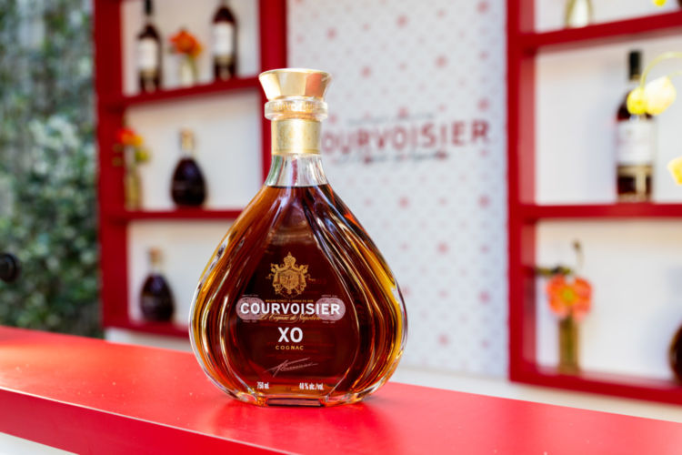 A bottle of Courvosier on a red bar.