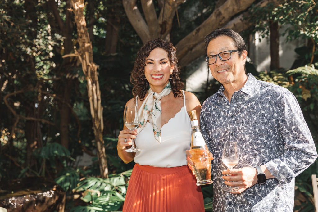 Guests smiling at the camera while holding a bottle and glasses.