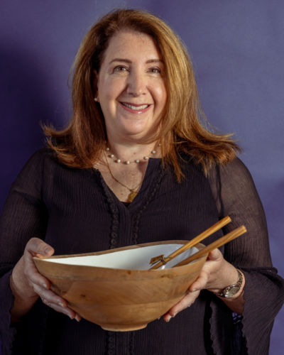 A woman in a dark shirt holding up a bowl.