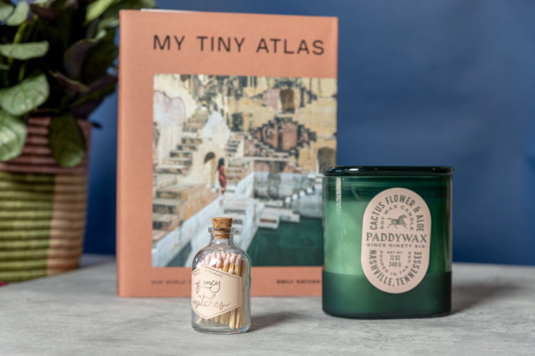 My Tiny Atlas book photographed with a bottle of fancy matches and a green candle jar.